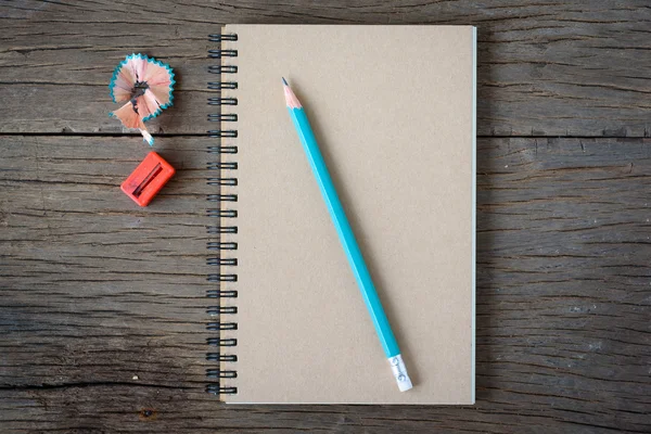 An opened notebook with pencil and Pencil Sharpener on old wooden table. — Stock Photo, Image