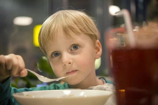 Piccolo ragazzo mangia al caffè con una forchetta, ritratto ravvicinato — Foto Stock