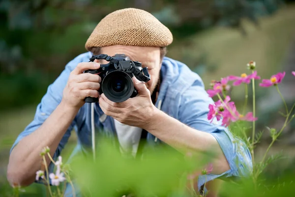 一个留着胡子的有趣的摄影师在公园里用相机拍照 — 图库照片