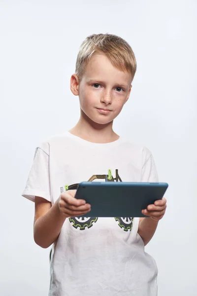 白いTシャツを着た10歳の少年がタブレット上でオンラインゲームをプレイ — ストック写真
