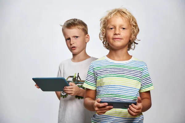 2人の男の子の友人はタブレットやスマートフォンでオンラインゲームをプレイ — ストック写真