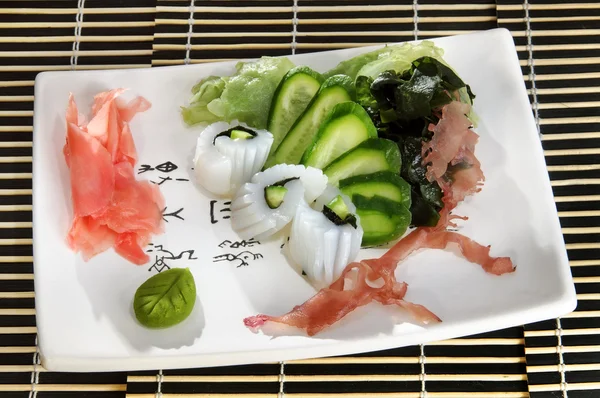 Sushi menu: shrimp with slices of cucumber and seaweed on a plate... — Stock Photo, Image