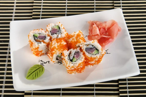 Sushi menu: a set of rolls with flying fish roe and avocado with wasabi and ginger on a plate — Stock Image Sushi menu: a set of rolls with flying fish roe and avocado with wasabi and ginger on a plate Stock Picture