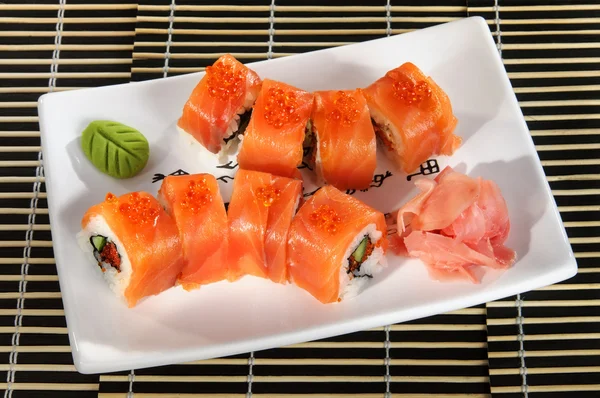 Sushi menu: a set of rolls of salmon and avocado with wasabi and ginger on a plate — Stock Image Sushi menu: a set of rolls of salmon and avocado with wasabi and ginger on a plate Stock Image