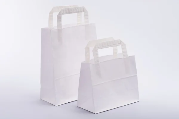 Saco de papel branco com alças em um fundo branco — Fotografia de Stock