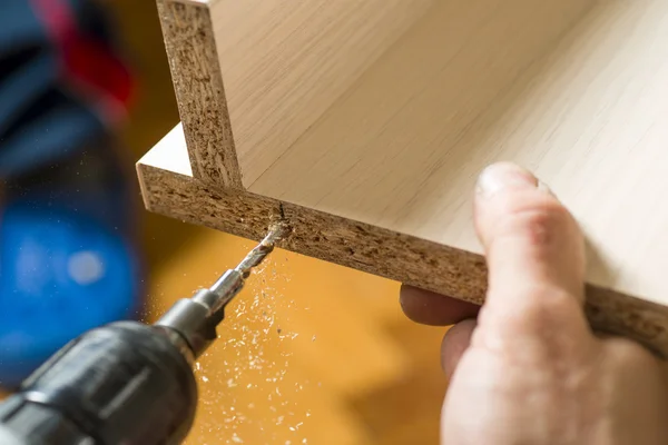 Montaje de muebles. Master perfora un agujero en el tablero de muebles . — Foto de Stock