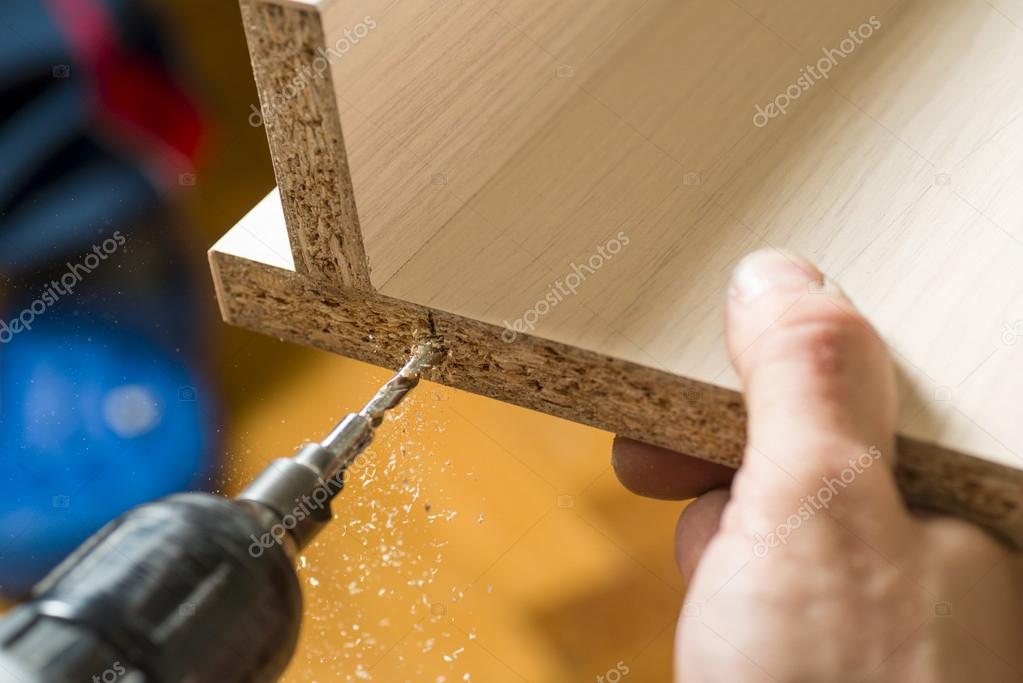 Furniture assembly. Master drills drill a hole in the furniture board