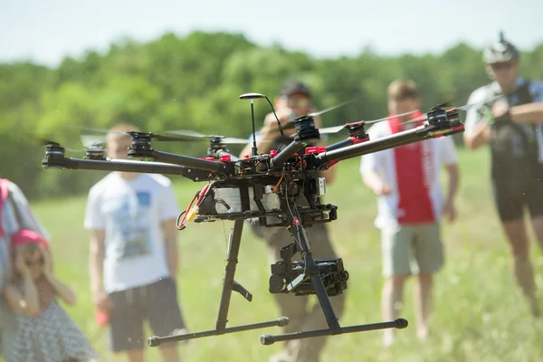 Quadrocopter drone in flight, there are people behind — Stock Photo, Image