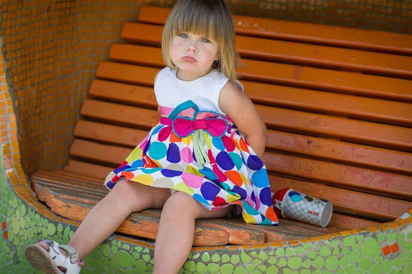Little girl on a bench in the park in the summer — Stock Photo, Image