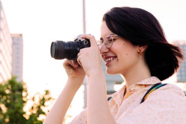 Güzel gezgin kadın gülümsüyor ve eski bir fotoğraf makinesiyle fotoğraf çekiyor, gençlik konsepti ve yaratıcı yaşam tarzı, metin için kopyalama alanı