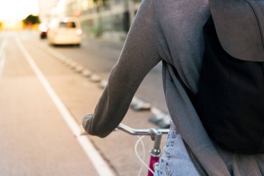 Şehirde sırt çantalı, pembe retro bisiklet süren, aktif yaşam tarzı ve sürdürülebilir hareketlilik kavramına sahip tanınmayan genç bir kadın.