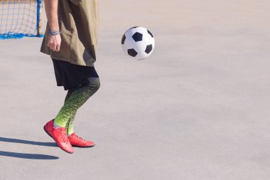 Beton bir futbol sahasında top oynayan tanınmayan futbolcu, şehirde sağlıklı yaşam tarzı ve şehir sporu kavramı, metin için kopya alanı