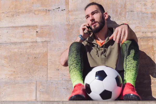 Futbol Topunun Yanında Dinlenirken Telefonda Konuşan Yakışıklı Sporcu Şehirde Teknoloji — Stok fotoğraf