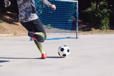 Bir futbol oyuncusunun futbol topunu beton bir futbol sahasında boş bir kaleye attığı arka plan, şehirde sağlıklı yaşam tarzı ve kentsel spor kavramı, metin için metin alanı kopyalama