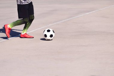 Tanınmayan bir futbolcunun ayakları beton bir futbol sahasında topla oynaması, şehirde sağlıklı yaşam tarzı ve şehir sporu kavramı, metin için yer kopyalamak.