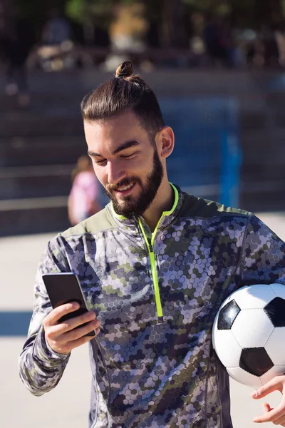 Deportista Moda Con Una Pelota Fútbol Sonríe Consultando Teléfono Móvil — Foto de Stock