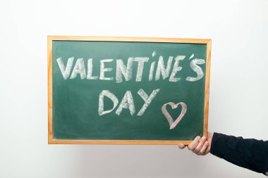 hand holding a chalkboard with the words VALENTINE'S DAY handwritten in chalk