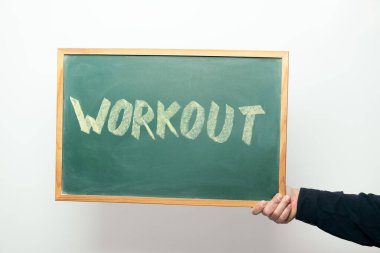 hand holding a chalkboard with the word WORKOUT handwritten in chalk