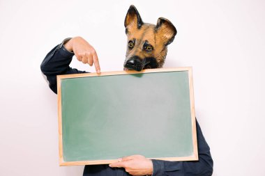 Köpek maskesi olan kişi beyaz arkaplanda boş bir sayfaya işaret ediyor, metin için alanı kopyala