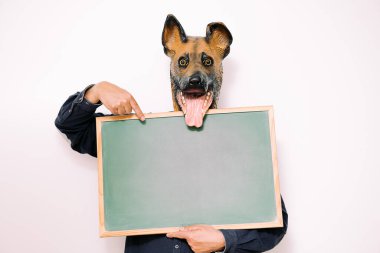 Mutlu köpek maskesi olan kişi beyaz arkaplanda boş bir işaret gösterir, metin için boşluk kopyala