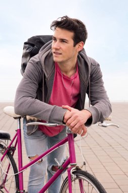 Bisiklete yaslanan yakışıklı bir gencin dikey fotoğrafı, ekolojik ve sürdürülebilir şehir ulaşımı kavramı, metin için kopyalama alanı