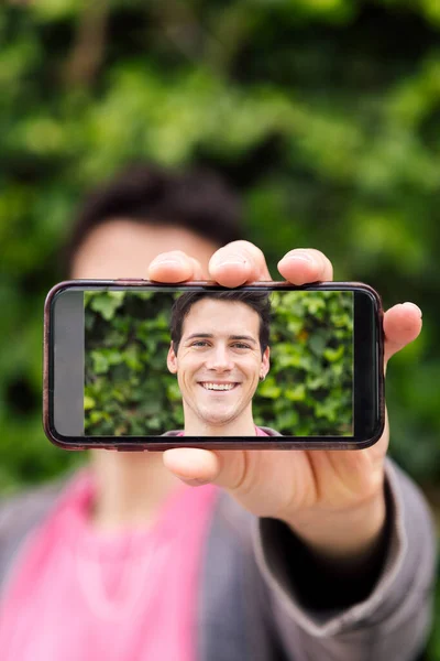 Вертикальна Фотографія Щасливого Молодого Чоловіка Закриває Обличчя Смартфоном Фотографією Себе — стокове фото