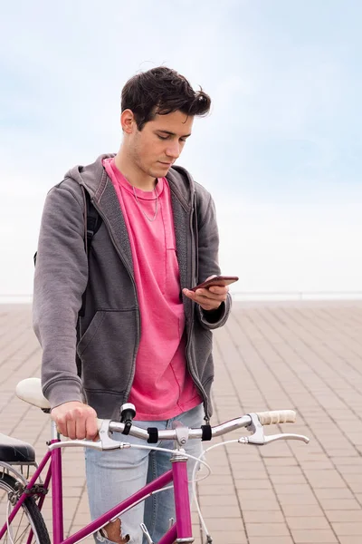 Foto Vertical Joven Sosteniendo Una Bicicleta Mientras Mira Teléfono Inteligente — Foto de Stock