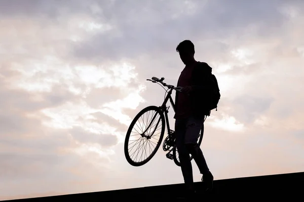 silhouette of a young man carrying bike down the stairs, concept of sustainable urban transportation and ecological lifestyle, copy space for text