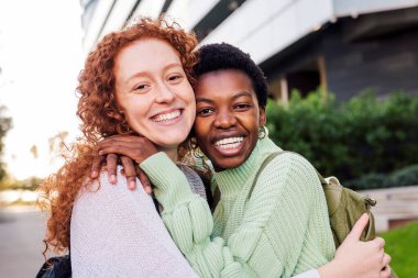 Kameraya, gençlik konseptine ve arkadaş yaşam tarzına bakıp gülümseyen iki genç kadının portresi