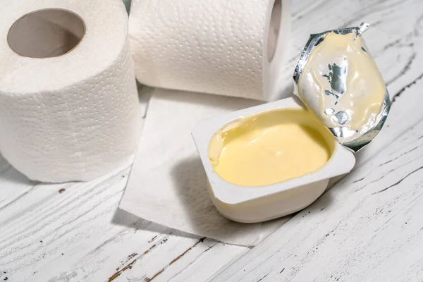 Pack of yogurt with tiolet paper on white wooden desk. — Stock Photo, Image