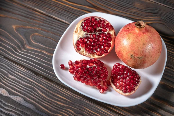 Craked ripe pomegranate on dark wooden background — Stock Photo, Image