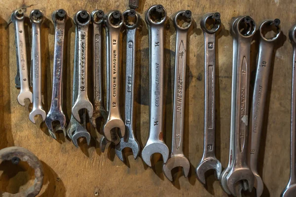 Duvarda asılı anahtar aletleri var. Tahta duvarda bir sürü İngiliz anahtarı var..