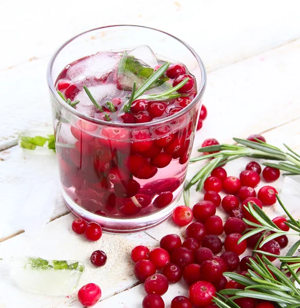 A glass of iced lemonade from cranberry, cranberries and rosemary on a white wooden background — Stock Photo, Image