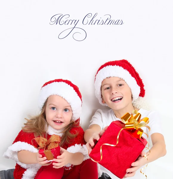 Cute girl and boy in Christmas hats with gifts — Stock Photo, Image