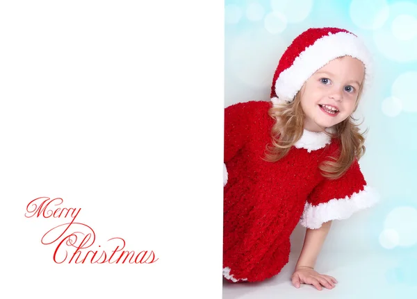 Girl in santa hat with Christmas peeping from behind — Stock Photo, Image