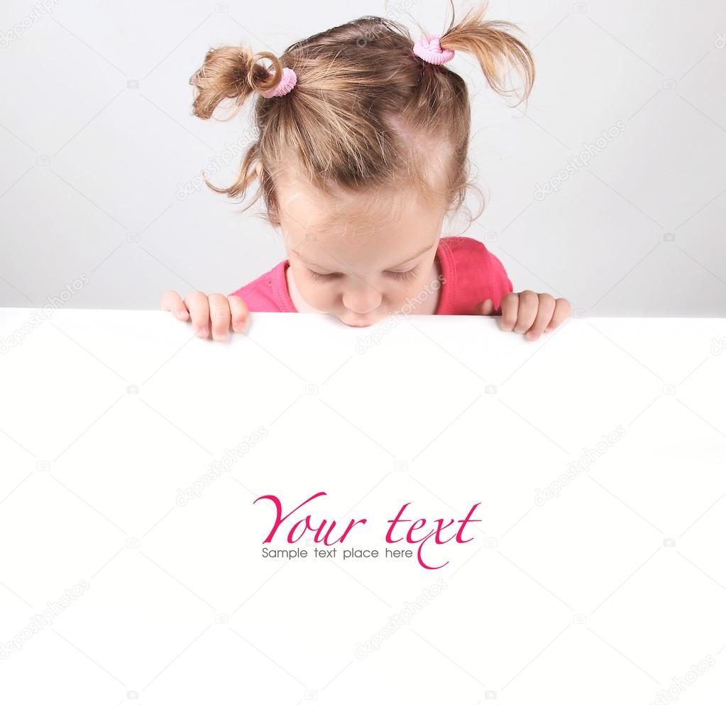 Happy little girl peeking out from behind a white advertisement board