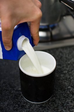 Tanımlanamayan el siyah bir kaba süt döküyor.