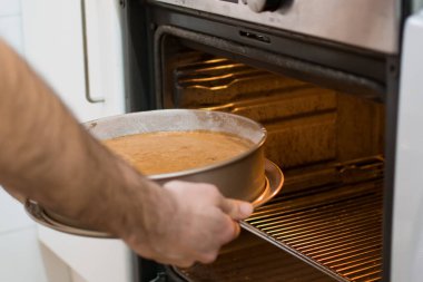 Tanınmayan eller fırına havuçlu kek koyuyor.