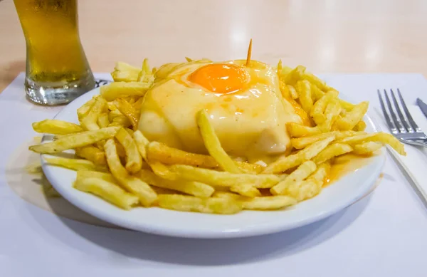 Peynirli etli sandviç ve yanında patates kızartması ve Francesinha adında bir yumurta Porto 'da bir restoranda birayla servis ediliyor. Geleneksel bir Portekiz yemeği ve çok kaloriktir.