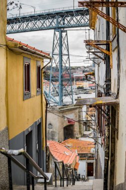 Porto, Portekiz 'in eski bir kasabasındaki bir sokaktan gördüğüm çift katlı metal kemerli köprü Dom Luis. Bulutlu bir gün ve Douro Nehri köprünün altından görülebilir..