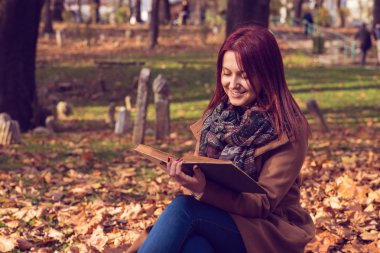 park ve okuma kitabı bankta oturan Kızıl saçlı kız