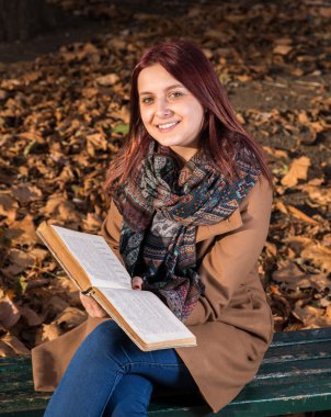 park ve okuma kitabı bankta oturan Kızıl saçlı kız