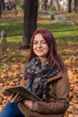 park ve okuma kitabı bankta oturan Kızıl saçlı kız