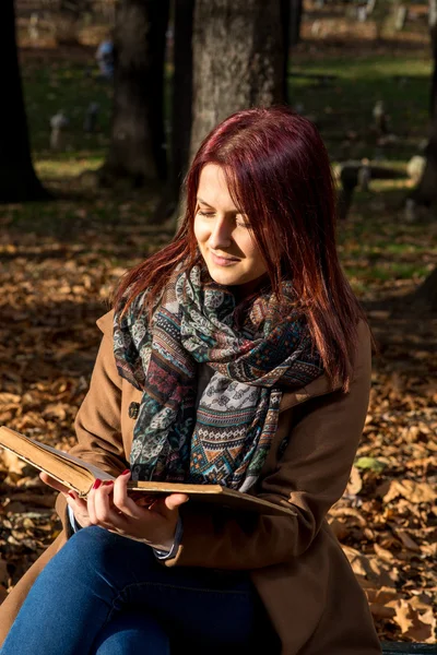 Redhead girl sitting on bench in park — Stock Photo, Image