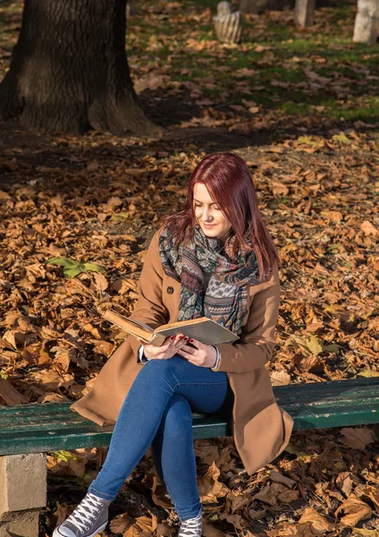 Redhead girl sitting on bench in park — Stock Photo, Image