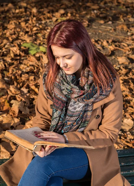 Redhead girl sitting on bench in park — Stock Photo, Image