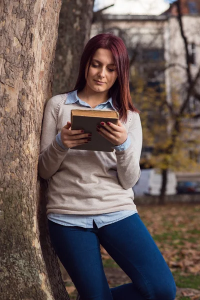 Universitet girl i park läser en bok — Stockfoto