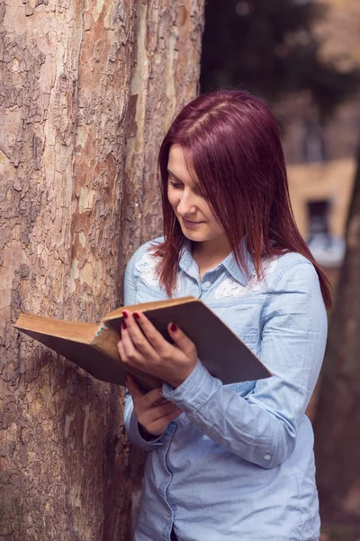 Universitet girl i park läser en bok — Stockfoto