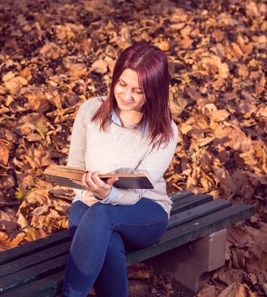 Girl sitting on bench in ark and reading a book — Stock Photo, Image