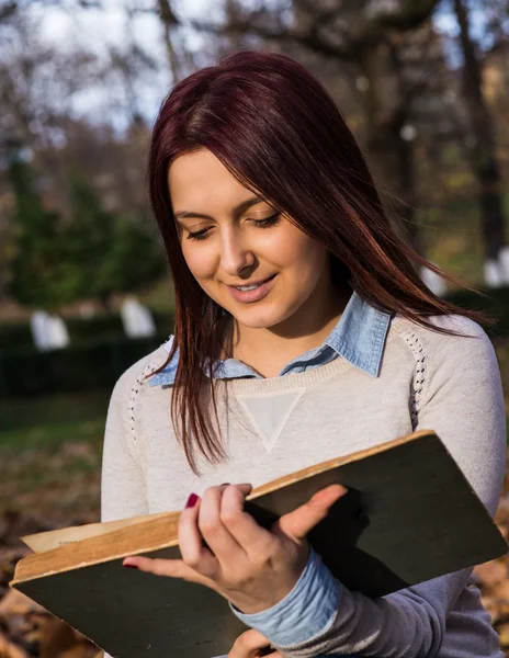 Universitetet flicka sitter i parken och läsa en bok — Stockfoto